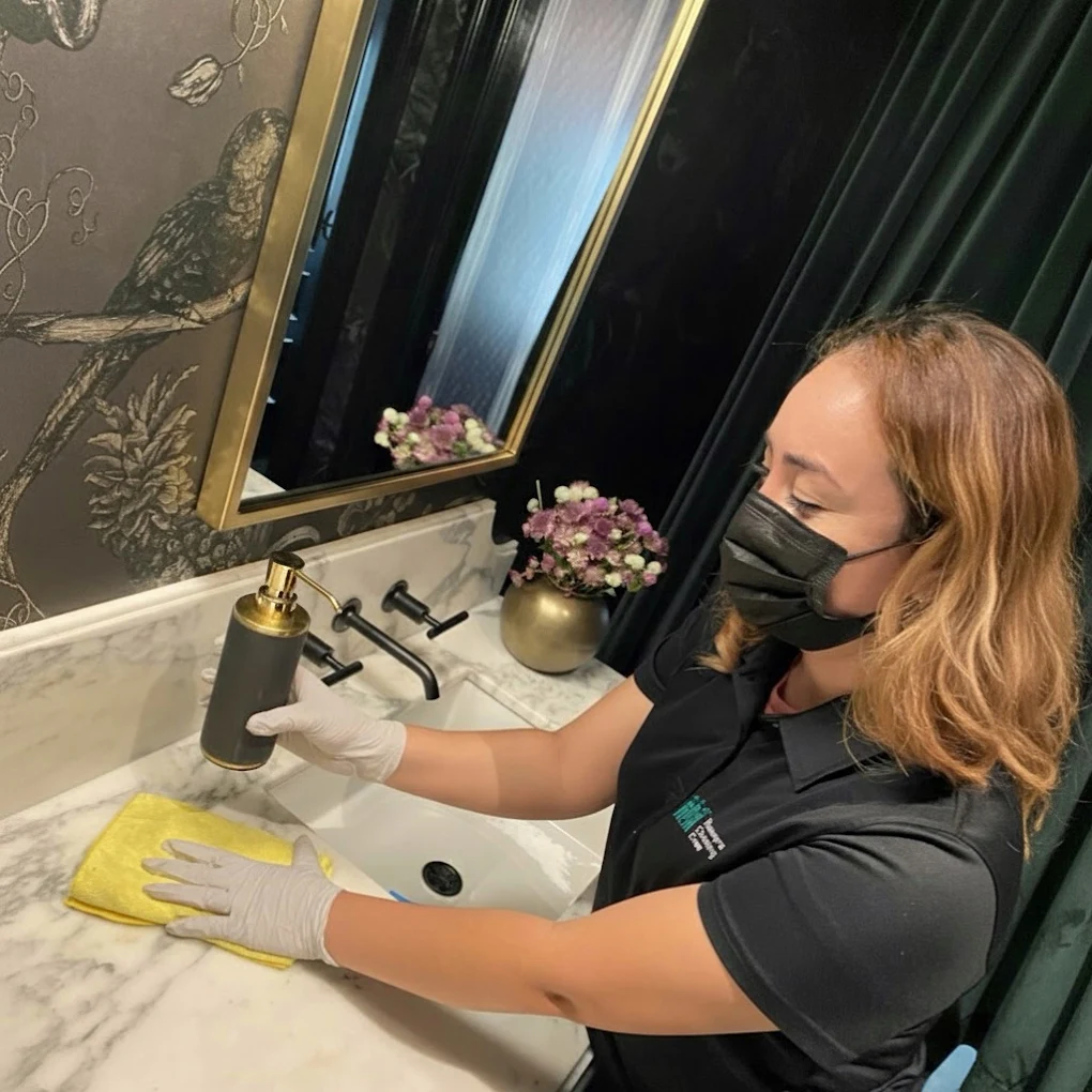 Illawarra Cleaning Crew cleaner wiping a marble vanity in a luxury powder room