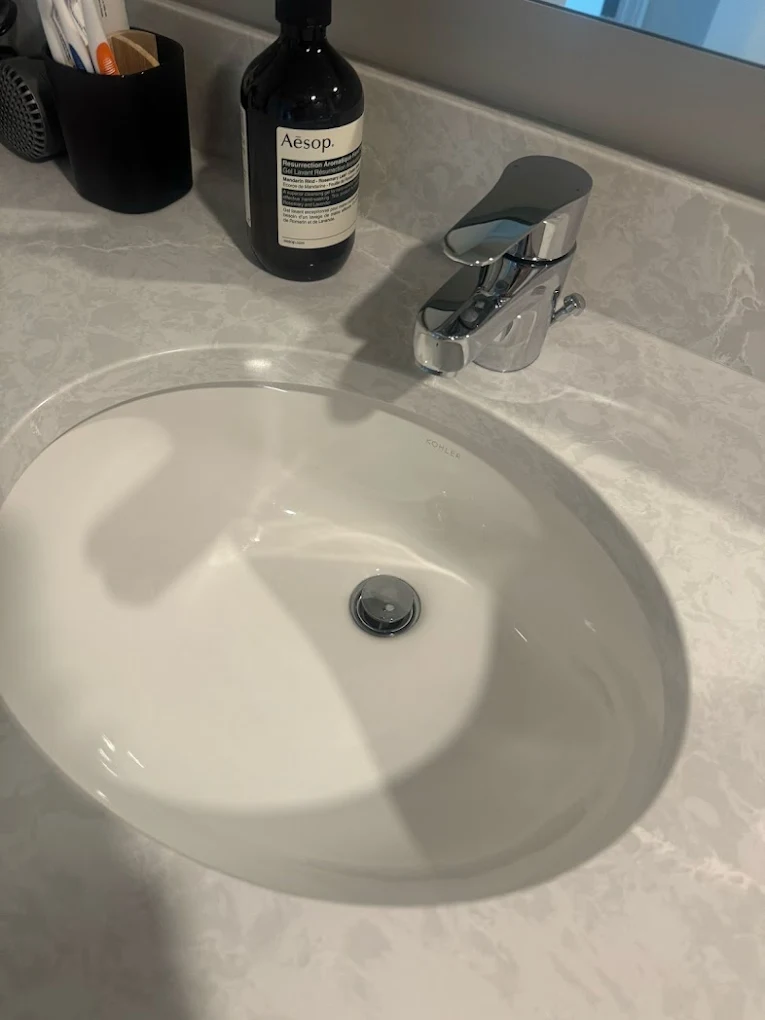 Close-up of a sparkling clean white ceramic basin on stone benchtop