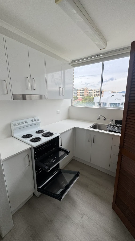 White unit kitchen with oven door open after vacate clean