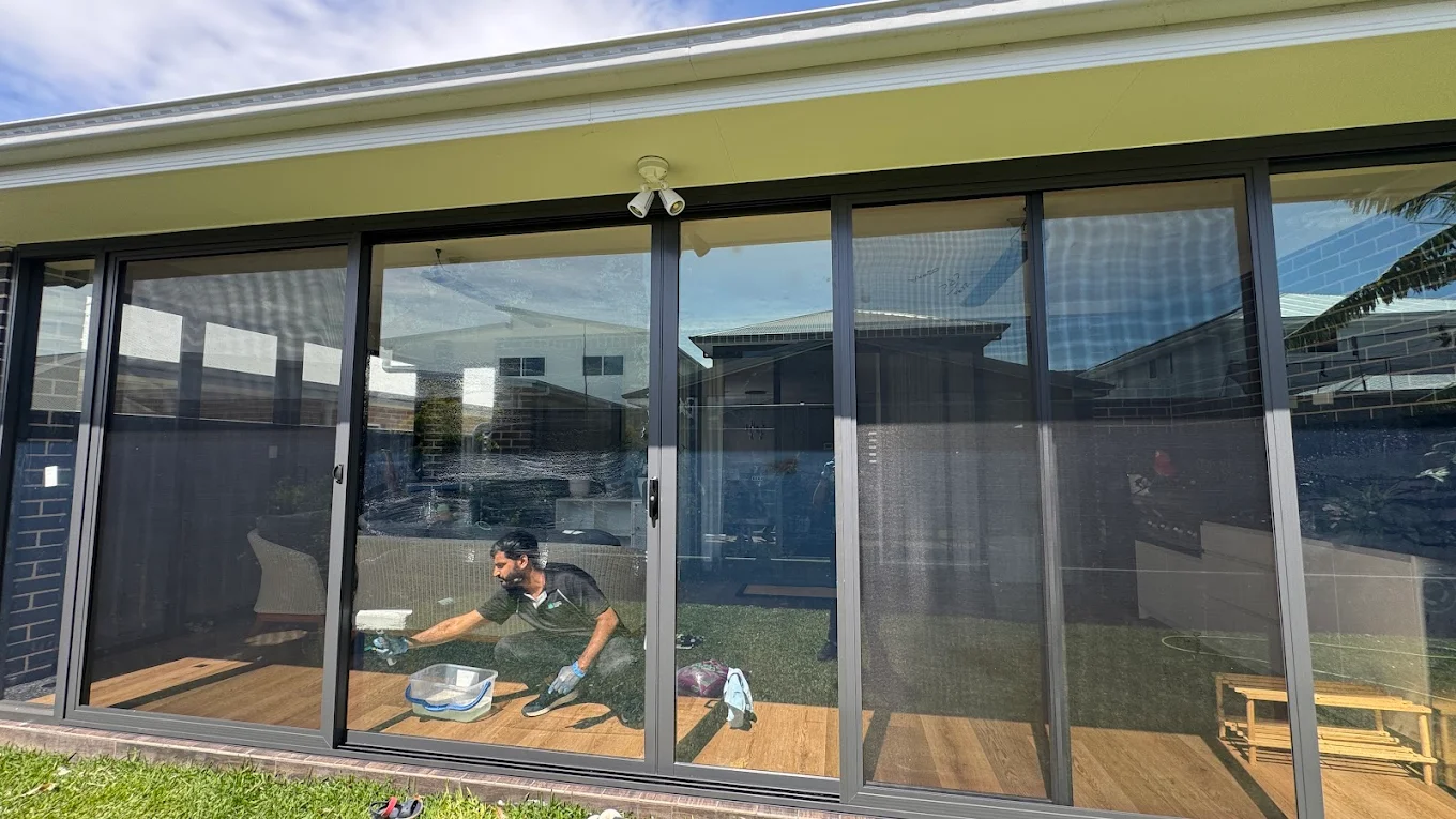 Cleaner reflected in freshly cleaned exterior sliding glass doors