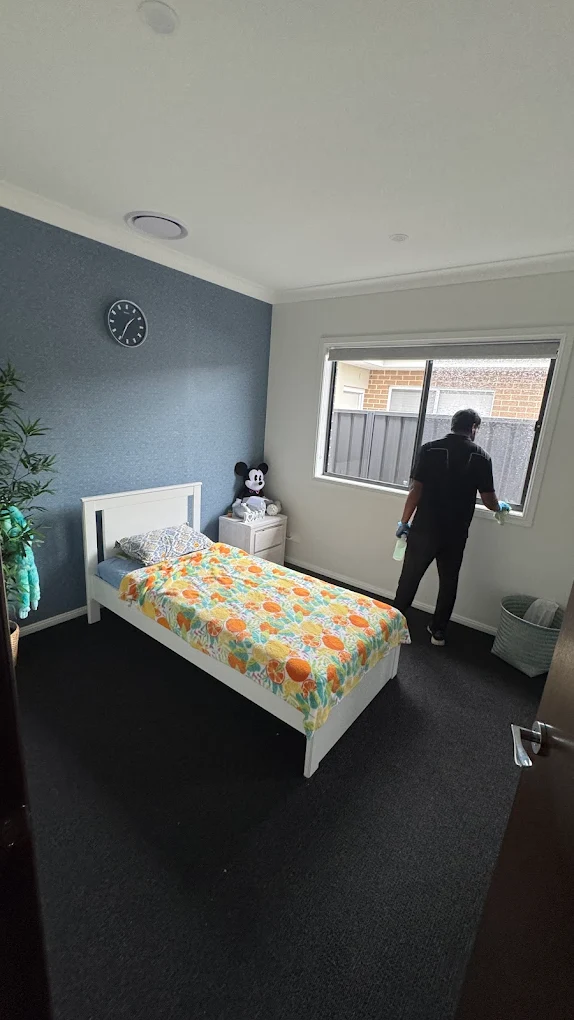 Cleaner detailing a bedroom window during a regular house clean
