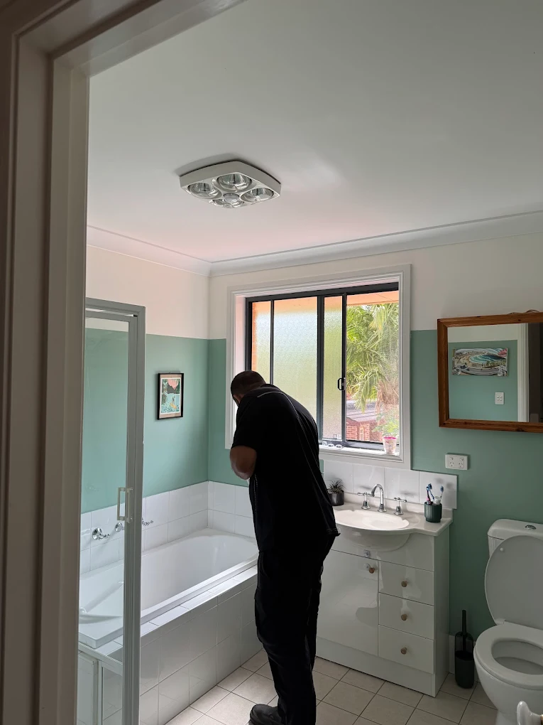 Cleaner detailing a mint-green family bathroom in Wollongong